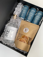 HM Gin London Dry 500ml bottle and Sodasmith tonic water cans in a gift box with a packet of Cocktail Candy dehydrated orange wheels. 
