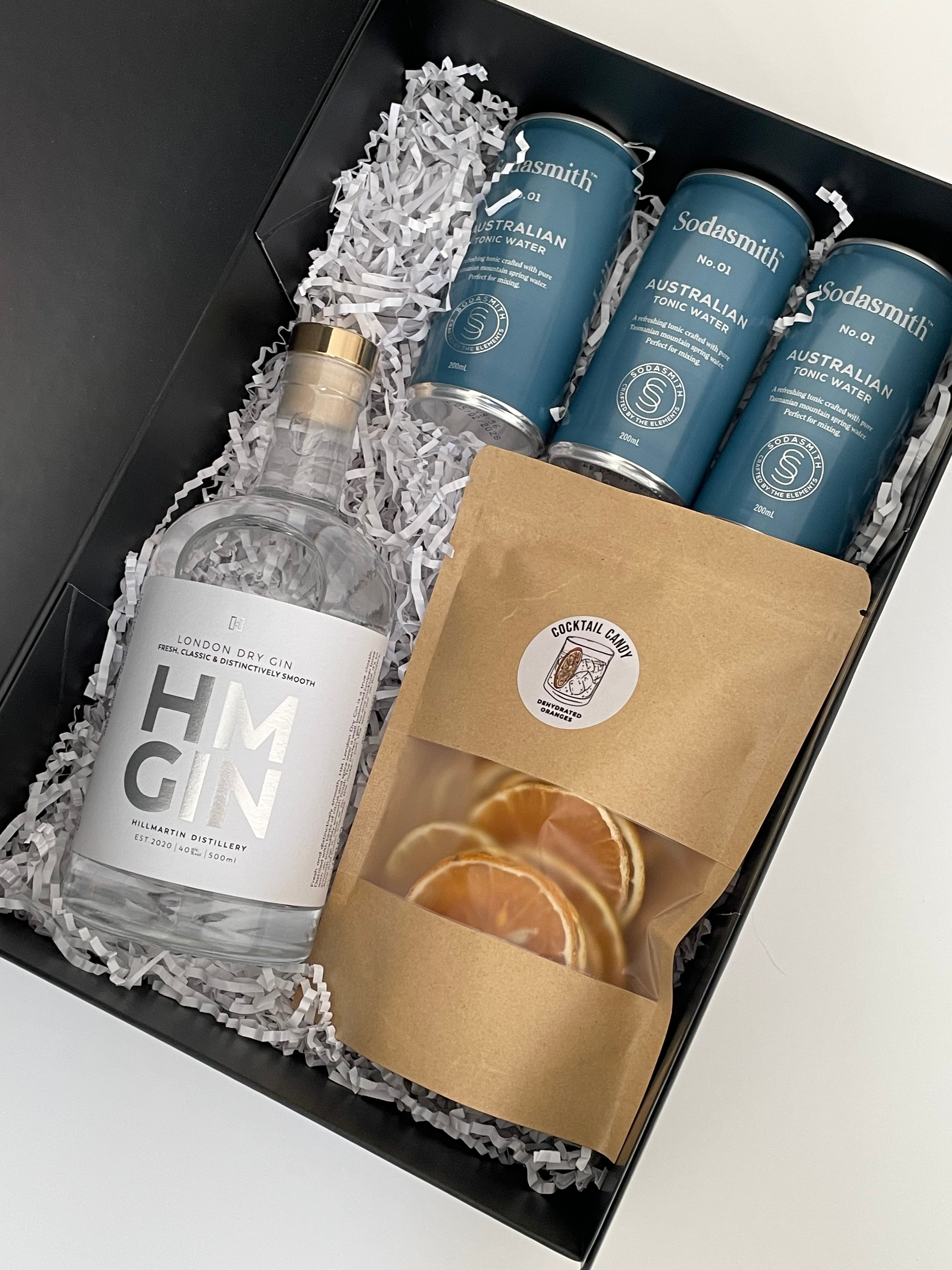 HM Gin London Dry 500ml bottle and Sodasmith tonic water cans in a gift box with a packet of Cocktail Candy dehydrated orange wheels. 