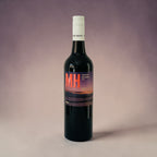 Wine bottle with a label featuring 'MH' on a gradient background
