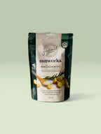 Packaged macadamias with rosemary and sea salt on a light green background
